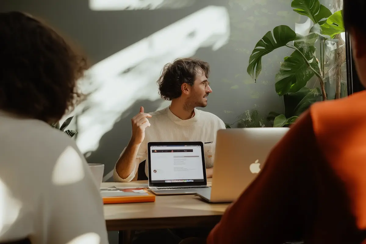 Homme en réunion de travail avec ordinateurs portables et collègues